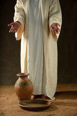 Jesus standing with a jar of water and a bowlの写真素材