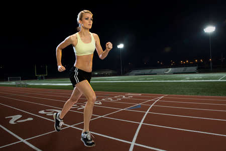 Woman running on a track at night