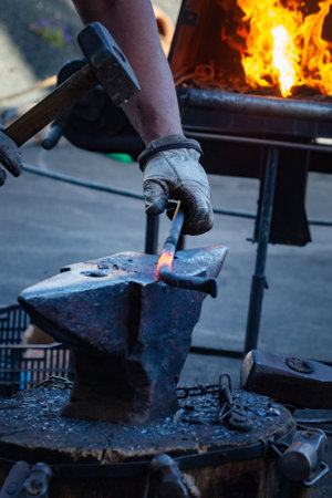 Blacksmith working with hot metal on the anvil in the forge