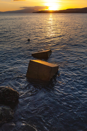 Sunset over the sea with a wooden breakwater in the foreground.