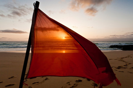 Sunset on the beach with a red umbrella in the foreground.の写真素材