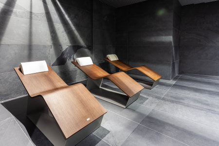 Interior of a modern hotel lobby with black marble walls and wooden chairs