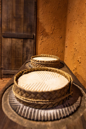 Traditional palm leaf baskets on a wooden shelf with cheeses