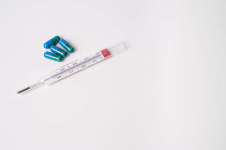 medicinal capsules and thermometer on white backgroundの写真素材