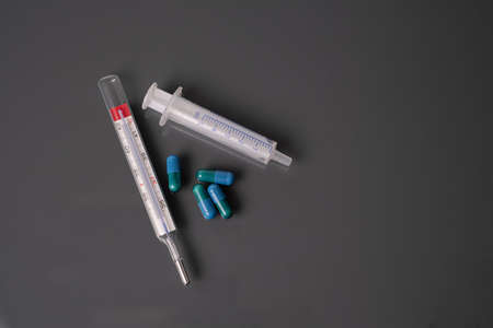 medicine thermometer and syringe dark background