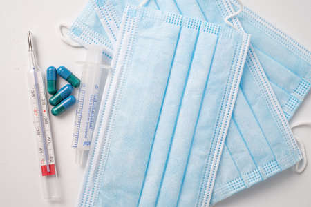 surgical mask medicinal capsules and thermometer on white background