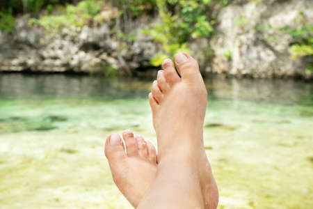 Female feet relaxing on cenoteの写真素材
