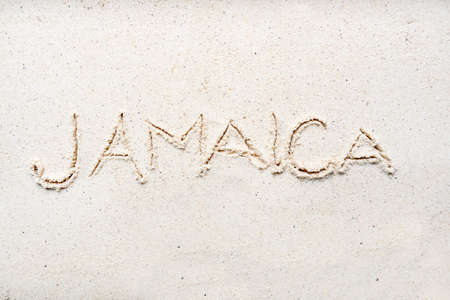 Handwriting words Jamaica on sand of beach