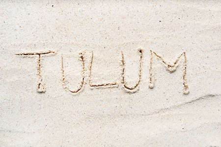 Handwriting words Tulum on sand of beach