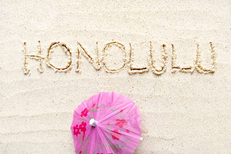 Handwriting words Honolulu on sand of beach