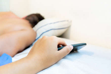 Young woman spying boyfriend mobile phoneの写真素材