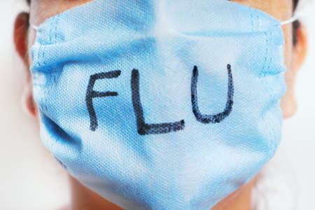 Flu concept with a young woman using blue medical mask