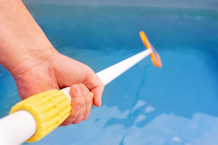 Male hand cleaning pool
