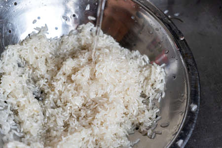 Washing white rice in metallic bowlの写真素材