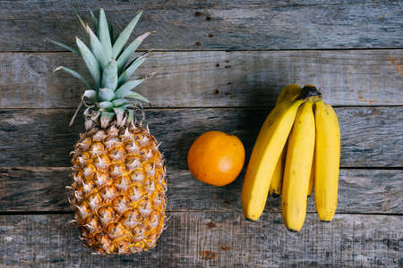 Bananas, orange and pineapple fruits on wood backgroundの写真素材