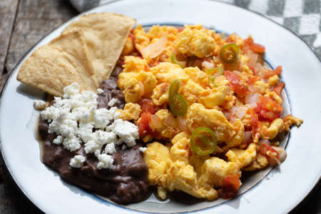 Mexican style scrambled eggs with fried beans, panela cheese and jalapenoの写真素材