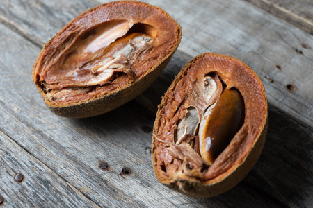 Tasty ripe mamey fruit with seed on wood background