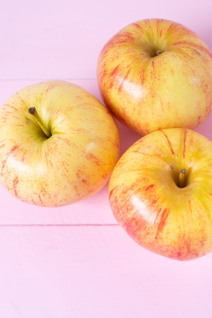 Set of red and yellow apples on wooden pink background