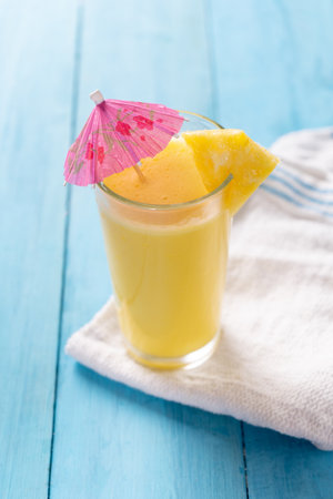 Pina colada cocktail with pink umbrella on blue backgroundの写真素材