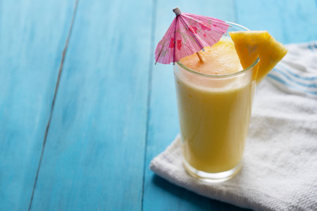 Pina colada cocktail with pink umbrella on blue backgroundの写真素材