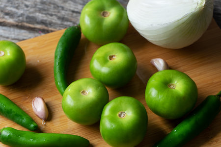 Mexican green sauce ingredients on wooden background