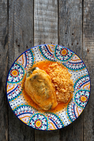 Traditional mexican stuffed chili pepper "filled" with tomato sauce and red rice on wooden backgroundの写真素材