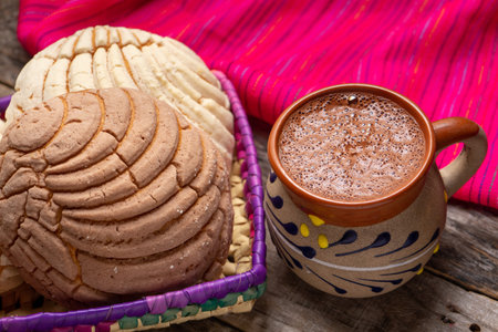 Traditional mexican hot chocolate with sweet conchas bread on wooden backgroundの写真素材