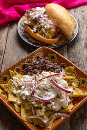 Traditional mexican green chilaquiles with cheese and sour cream on wooden backgroundの写真素材