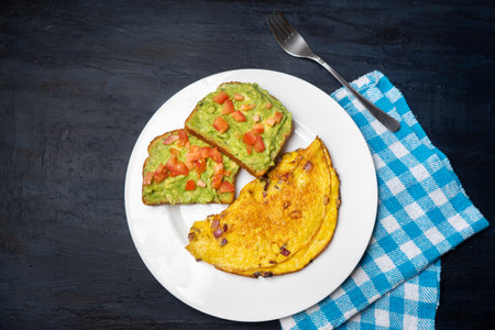 Healthy breakfast with egg omelette and guacamole toast on dark backgroundの写真素材