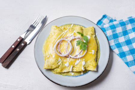 Traditional mexican green enchiladas with melted cheese also called "suizas" on white backgroundの写真素材