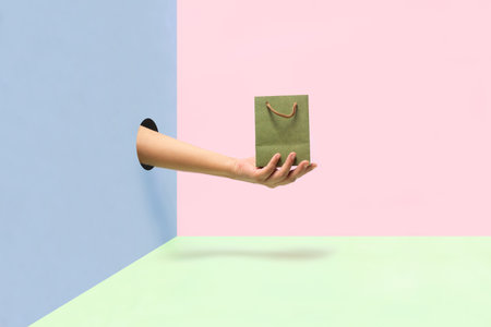 Female hand holding a paper bag on colorful background.の写真素材