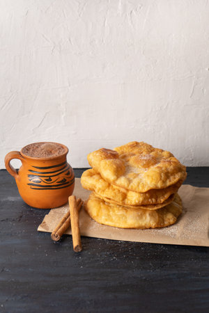 Traditional mexican fritter dusted with sugar also called buÃ±uelos and hot chocolate on rustic...