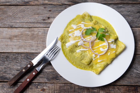 Traditional mexican green enchiladas with melted cheese also called "suizas" on wooden backgroundの写真素材