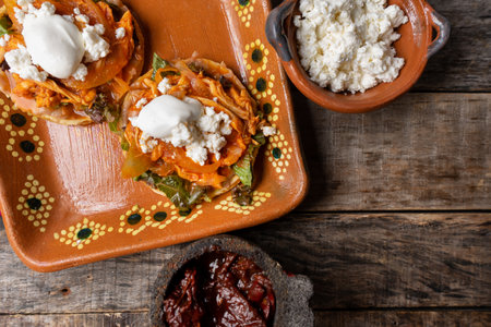 Traditional mexican chicken tinga sopes with chipotle pepper and fresh cheese on wooden backgroundの写真素材