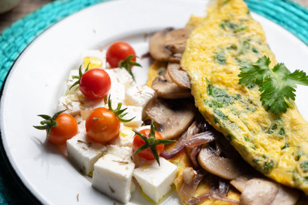 Mushroom omelette with fresh cheese and cherry tomatoes on wooden backgroundの写真素材