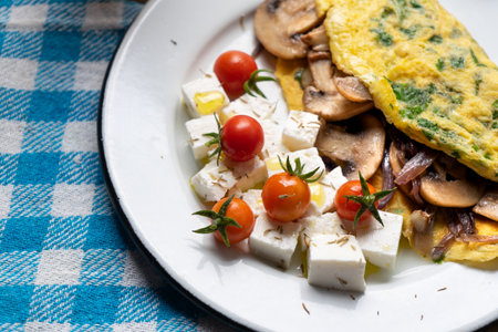 Mushroom omelette with fresh cheese and cherry tomatoes on wooden backgroundの写真素材