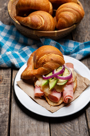 Traditional butter croissant bread with ham and cheese on wooden backgroundの写真素材