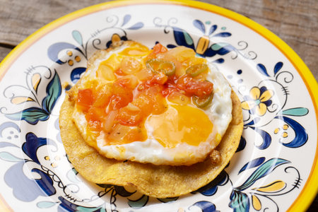 Traditional mexican egg mounted on corn tortilla with sauce also called "rancheros" on wooden backgroundの写真素材