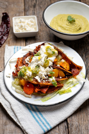 Traditional mexican red enchiladas with potato and pork chorizo also called Potosinas on wooden...