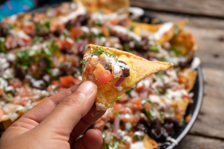 Traditional mexican nachos with beans and pico de gallo sauce on rustic background