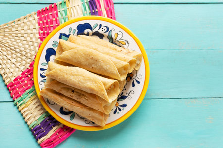 Traditional mexican potato and cheese fried tacos also called flautas on turquoise backgroundの写真素材