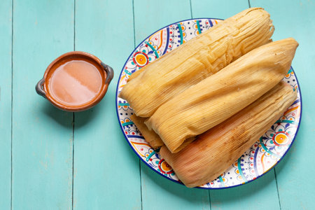 Traditional mexican tamales with red sauce on turquoise backgroundの写真素材