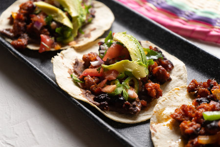 Traditional mexican pork chorizo tacos with avocado and beans on white backgroundの写真素材