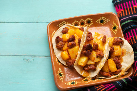 Traditional mexican chorizo with potatoes tacos on turquoise background