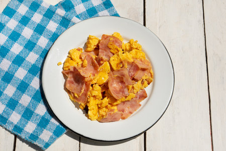 Scrambled eggs with ham for breakfast on white backgroundの写真素材
