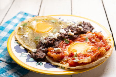 Traditional mexican fried eggs with green and red sauce also called "divorciados" on white backgroundの写真素材