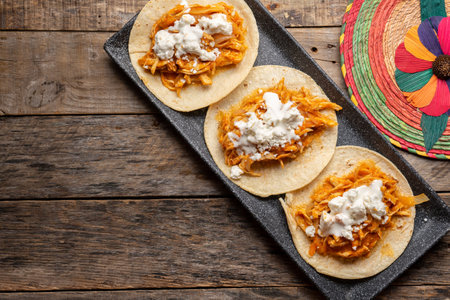 Traditional mexican chicken tinga tacos with chipotle sauce on wooden background