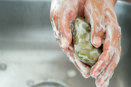 Washing hands with green soap bar and waterの写真素材