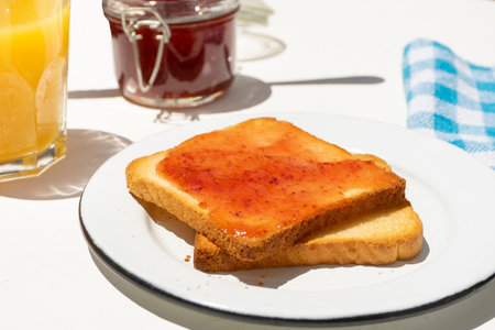 Bread toast with orange juice and strawberry jam on white background