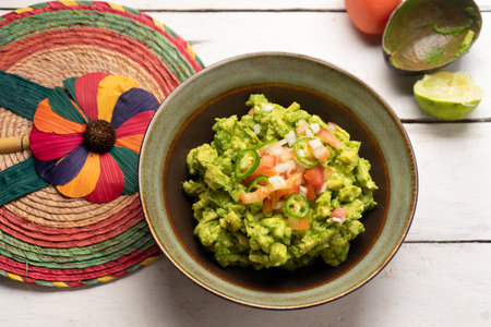 Traditional mexican guacamole with tomato and serrano pepper on white backgroundの写真素材
